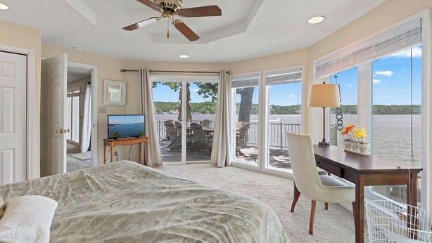 A bedroom with a bed, a desk, and a view of the outdoors. - Winding Bay - Lakefront with stellar main channel views! (Sunrise Beach)