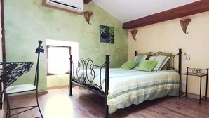 Een slaapkamer met een bed, een bureau, een stoel, een airconditioning en een raam.