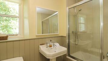 A bathroom with a toilet, a sink, a mirror, and a glass-enclosed shower.