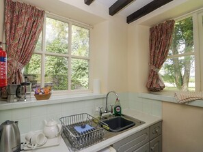 A kitchen with a window, a sink, and a kettle.