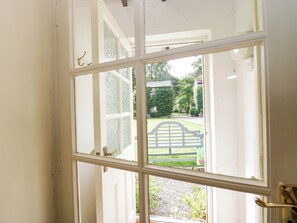 An open door with a view of a garden and a bench outside. - The Gameskeepers Cottage (Grange-over-Sands)