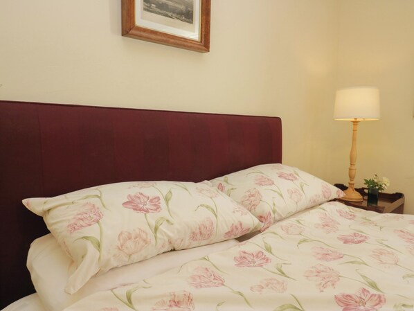 A bed with floral bedding and a wooden headboard.
