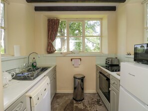 A compact kitchen with a sink, a washing machine, a trash bin, and a toaster. - The Gameskeepers Cottage (Grange-over-Sands)