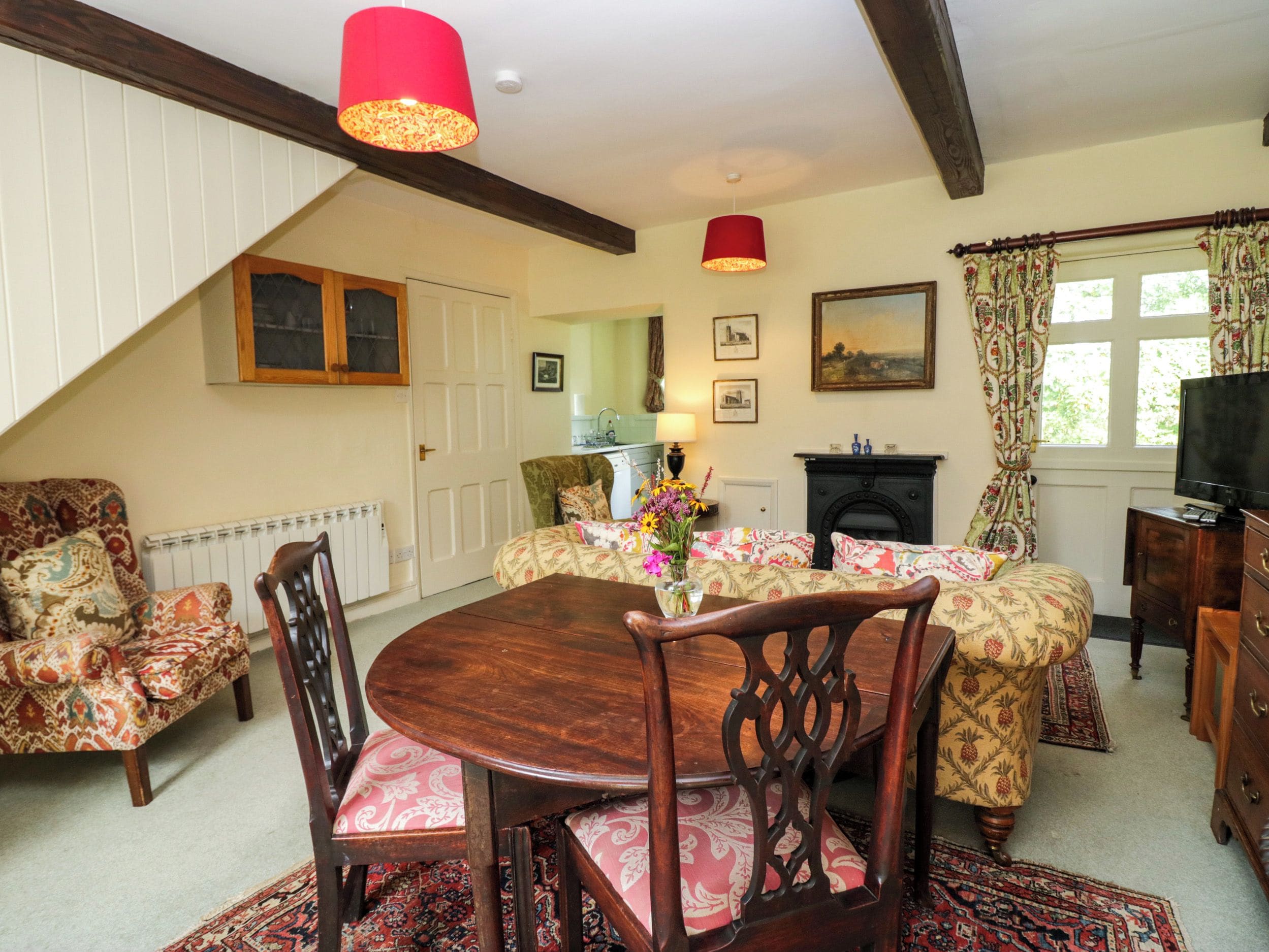 A cozy living room with a dining table, chairs, a fireplace, and a television.