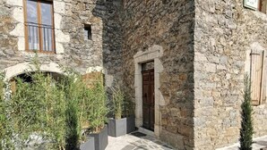 Un edificio de piedra con una puerta de madera, una ventana y un pequeño arco.