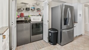 Una cocina compacta con un refrigerador de acero inoxidable, horno empotrado y un cesto de basura.
