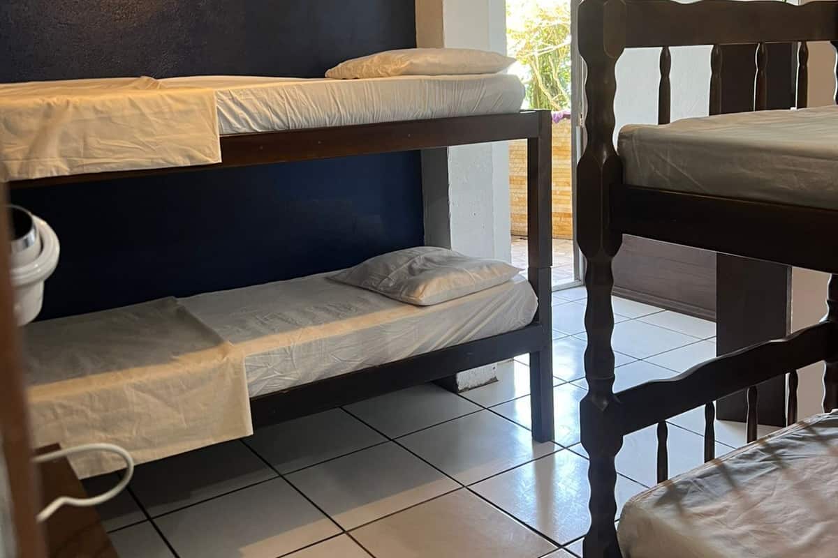 Une chambre de dortoir avec des lits superposés, un luminaire au plafond et une vue sur l’extérieur.