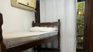 A bunk bed room with a ceiling fan, a window with a curtain, and a door with a view of greenery outside. - Villa Explorer (Imbituba)