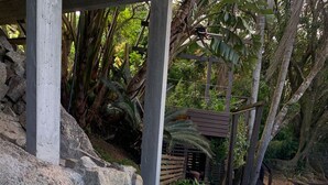 A swimming pool with a blue tiled edge, surrounded by natural vegetation and wooden structures. - Villa Explorer (Imbituba)