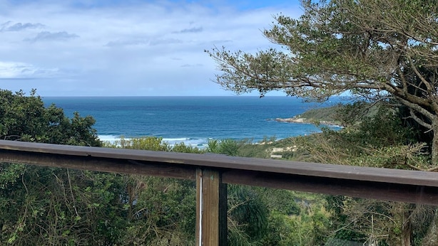 A balcony with a view of the ocean and coastal vegetation. - Villa Explorer (Imbituba)