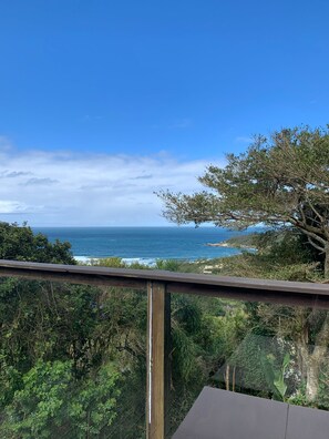 A balcony with a view of the ocean and coastal vegetation. - Villa Explorer (Imbituba)