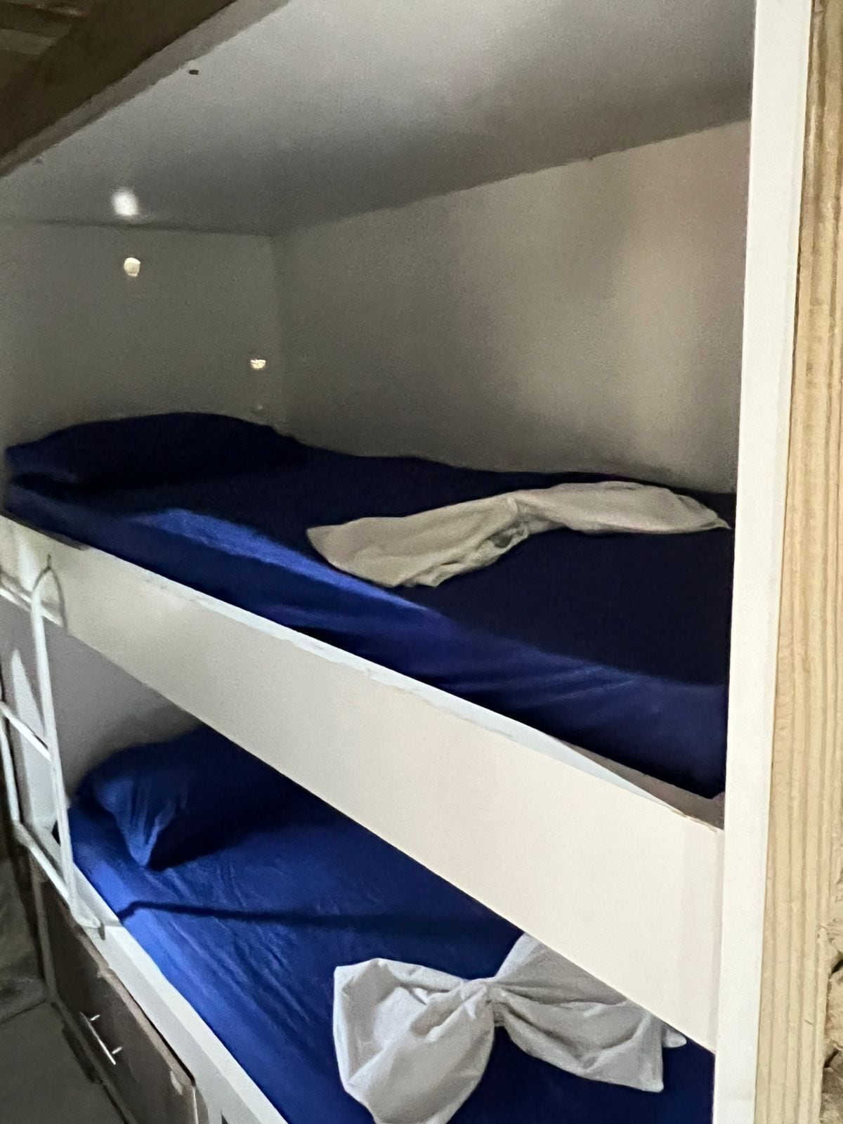 Una cama litera con ropa de cama azul y una almohada blanca.