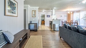 Een ruime woonkamer met een bank, een salontafel, en een eethoek met stoelen.