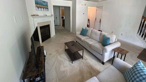 Un salon avec une cheminée, un canapé, une table basse et un ventilateur de plafond.