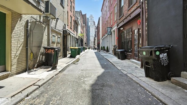 A narrow urban street lined with multi-story buildings, some with visible commercial signage. - Cozy Studio Retreat in Philadelphia (Philadelphia)