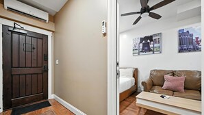 Una sala moderna con cama, un sofá de cuero marrón y un ventilador de techo.