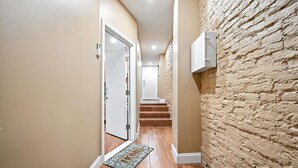 A hallway with wooden flooring, a doormat, and a brick wall. - Spacious Family-Friendly Home in Philadelphia (Philadelphia)