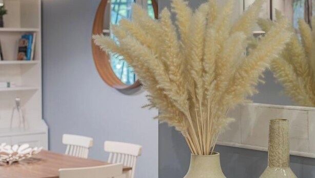 Un comedor con mesa y sillas, un jarrón con plumas de pluma y un espejo en la pared.
