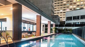 A pool area with a modern design, including a seating area with sofas and a railing.