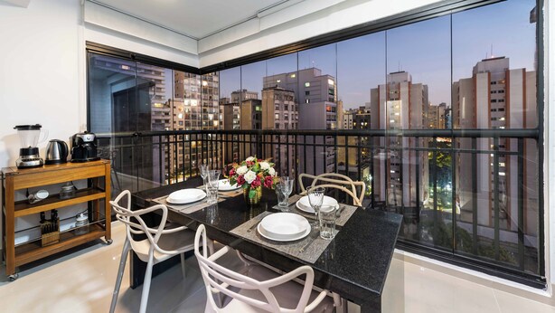 A dining area with a city view, a coffee maker, and a vase of flowers.