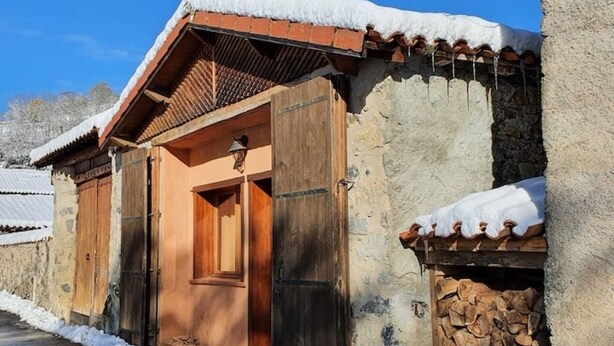 Un bâtiment traditionnel en pierre, doté d’une porte en bois et d’un petit porche.