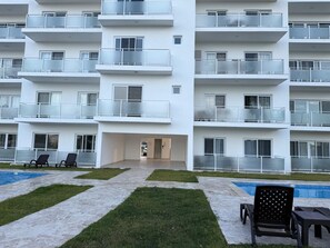 A modern multi-story building with balconies, a swimming pool, and outdoor seating. - Charming 1-bedroom apartment in enchanting Sosúa with AC, amazing restaurant (Sosúa)