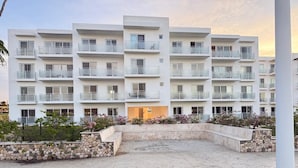 Ein mehrstöckiges Hotel mit Balkonen, einem Kiesweg und einem angelegten Garten.