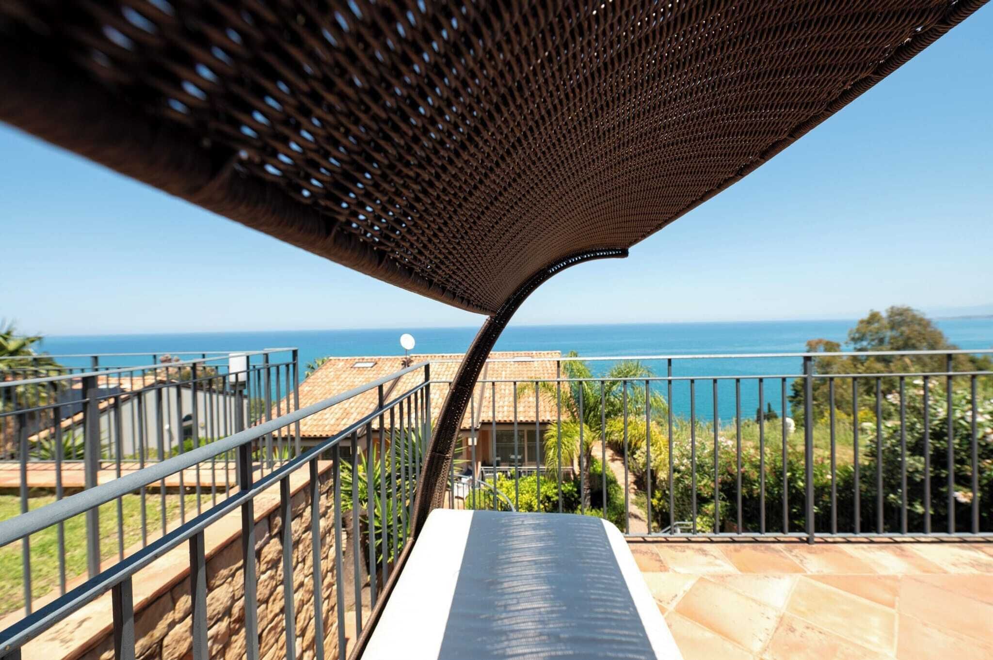 Un balcone con vista sul mare, una pergola e un muro in pietra.