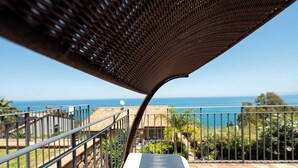 A balcony with a view of the sea, a pergola, and a stone wall.