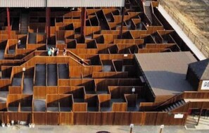 Een groot, meerlaags houten gebouw met veel zitplaatsen en trappen.