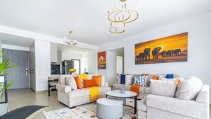 Ein modernes Wohnzimmer mit einer Sofagarnitur, einem Couchtisch und einem Teppich. An der Wand hängt ein Bild von Elefanten.
