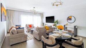 Ein modernes Wohnzimmer mit einer Sofagarnitur, einem Esstisch und einem flachbildfernseher an der Wand.