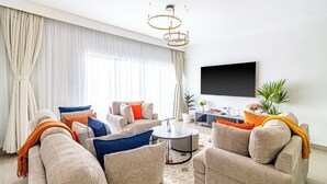 Ein modernes Wohnzimmer mit einer Sofagarnitur, einem Couchtisch und einem an der Wand montierten Fernseher.
