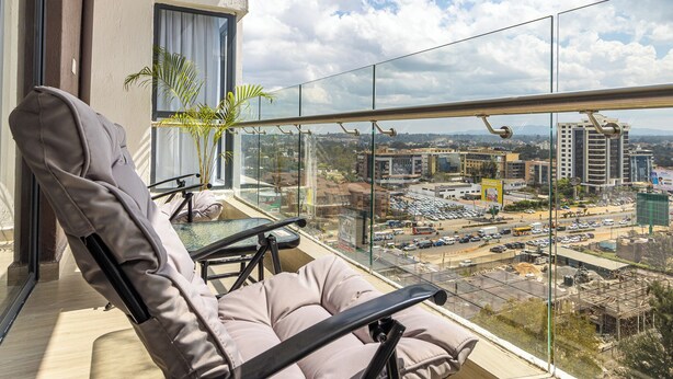 Ein Balkon mit gepolstertem Stuhl, einem kleinen Tisch und einem Blumentopf.