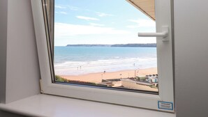 A window with a view of a beach and a distant shoreline. - Beachside (Paignton)