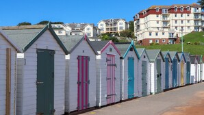 A row of colorful beach huts with a residential area in the background. - Beachside (Paignton)