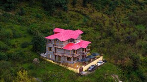 A multi-story house with a red roof, surrounded by lush greenery and hills. - Offbeat Pulga by PACK (Sosan)