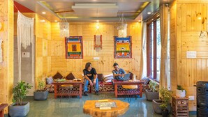 A wooden interior with two people sitting on sofas, a coffee table with a board game, and several potted plants. - Offbeat Pulga by PACK (Sosan)