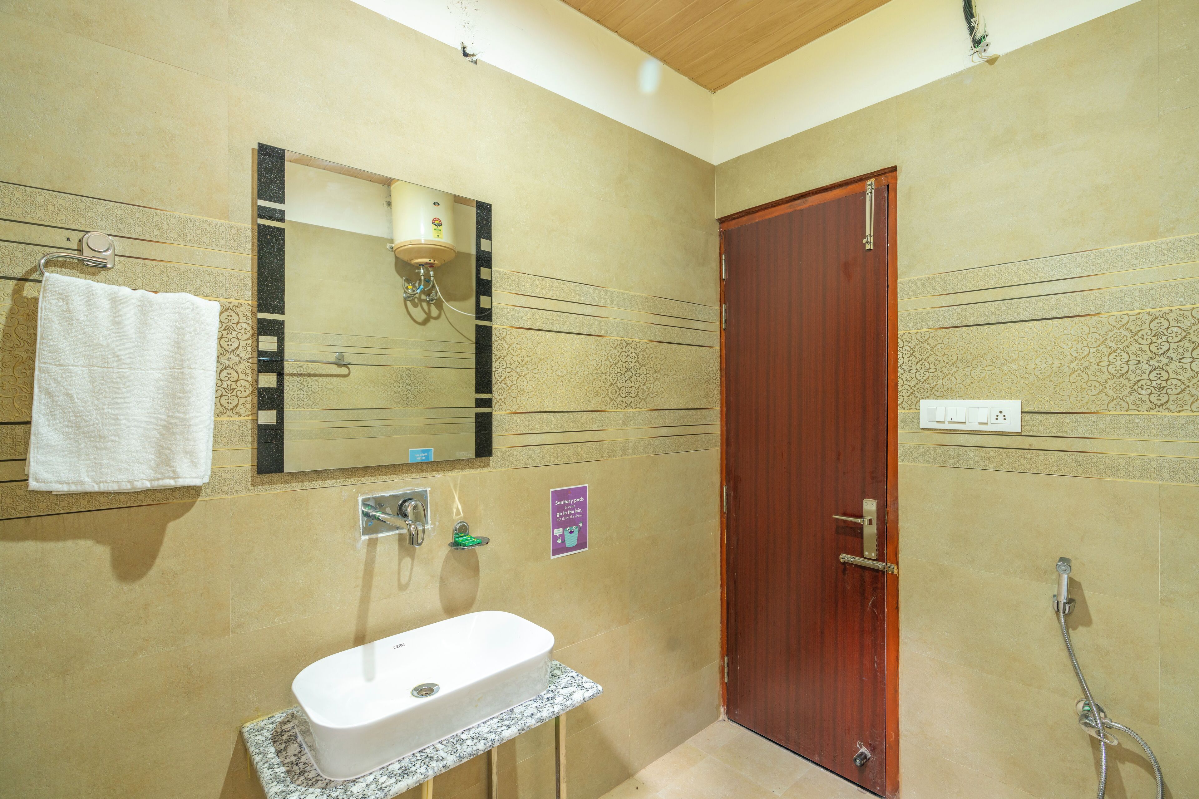 A bathroom with a sink, mirror, towel rack, shower, and a wooden door.