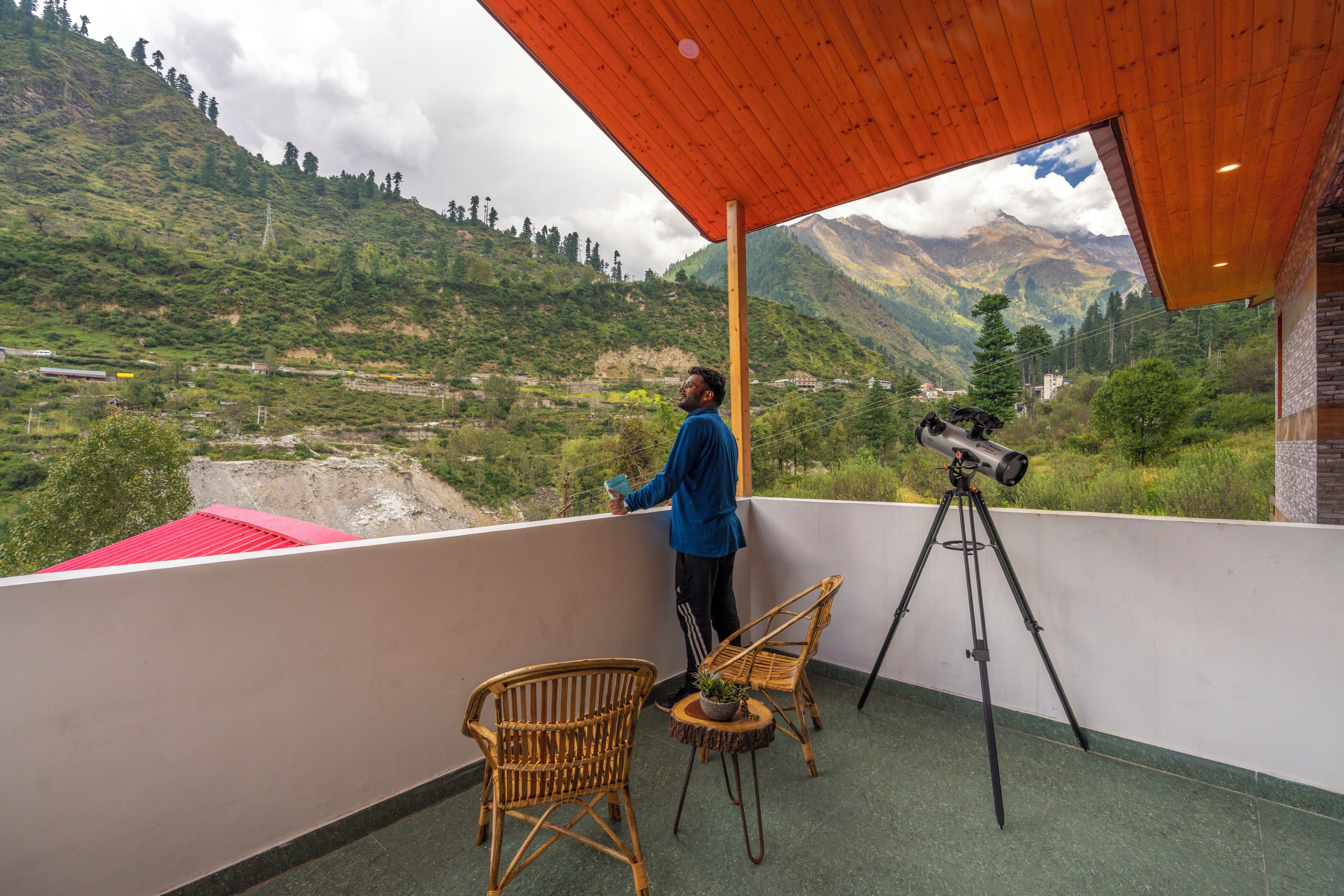 A balcony with a wooden ceiling, wicker chairs, and a telescope.