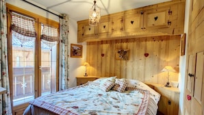 Ein gemütliches Schlafzimmer mit einem großen Bett, Holzwänden und einer Deckenleuchte.