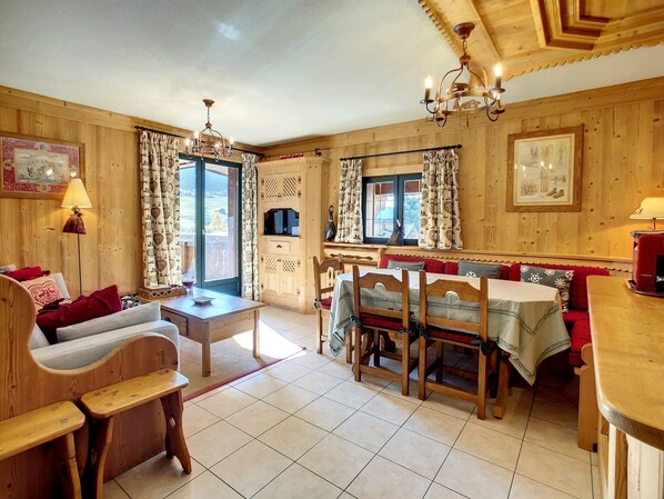 Un interior de madera acogedor con comedor, sofá y una mesa con sillas.