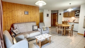 Ein gemütliches Wohnzimmer mit einer Couch, Sesseln, einem Couchtisch und einem Essbereich mit einem Holztisch und Stühlen.