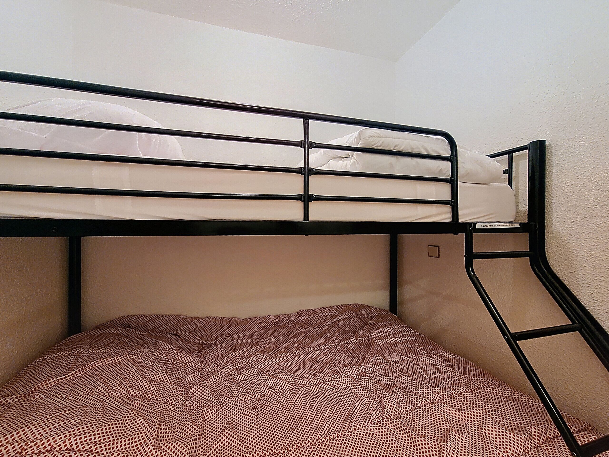 A bunk bed with a patterned bedspread and a ladder leading to the upper bunk.