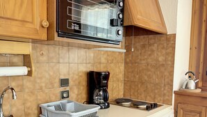 Une cuisine compacte avec des meubles en bois, un four à micro-ondes encastré, une machine à café et un lave-vaisselle.