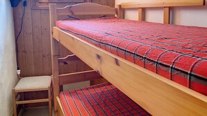 Une chambre avec un lit superposé, une fenêtre, un tableau et une lampe.