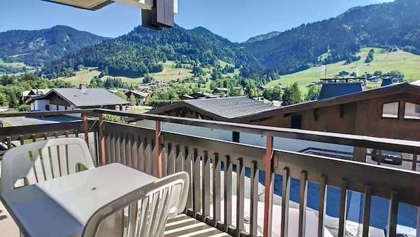 Un balcon donnant sur un paysage montagneux, avec une table et des chaises.