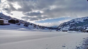 Un paysage enneigé, avec des bâtiments et des montagnes en arrière-plan.