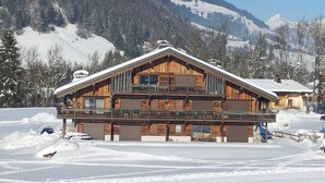 Un chalet en bois doté d’un balcon, entouré de montagnes enneigées.