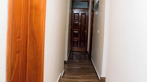 A hallway with wooden flooring and white walls, leading to a door at the end.